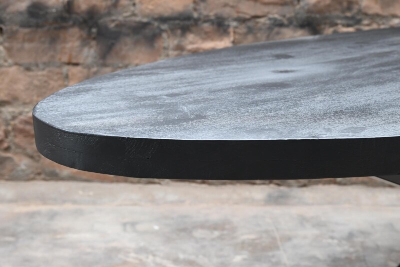 Robuster Esszimmertisch oval aus schwarzem Mangoholz.