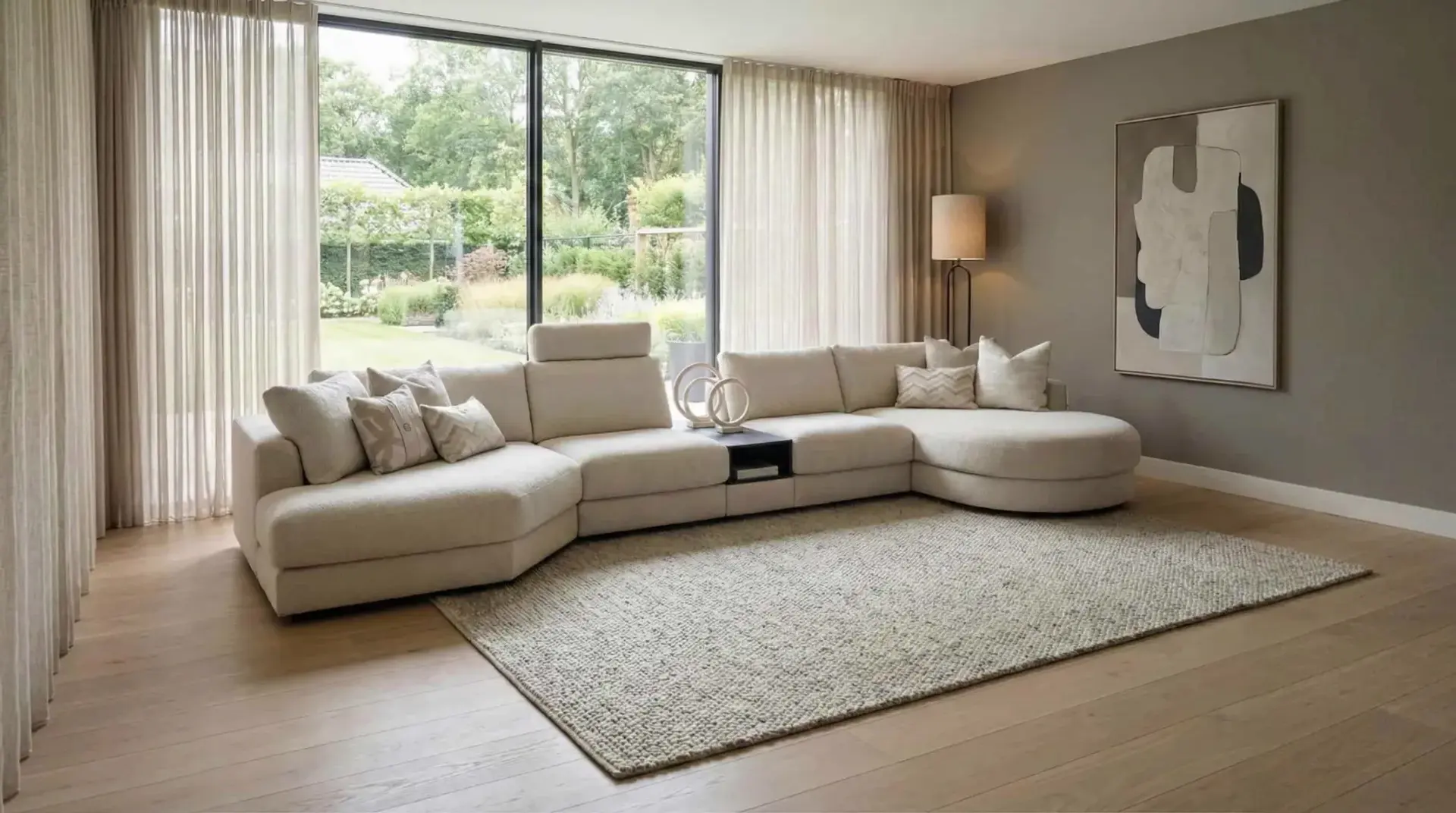 Grosses beiges Ecksofa Mirable mit Recamiere in einem hellen Wohnzimmer mit grosser Fensterfront zum Garten