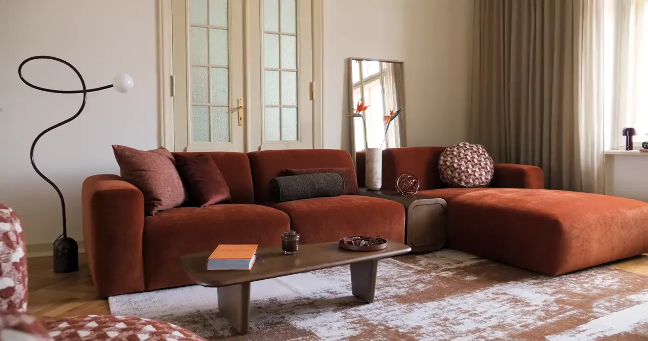 Ecksofa Vendi in warmem Rostton in einem hellen Wohnzimmer